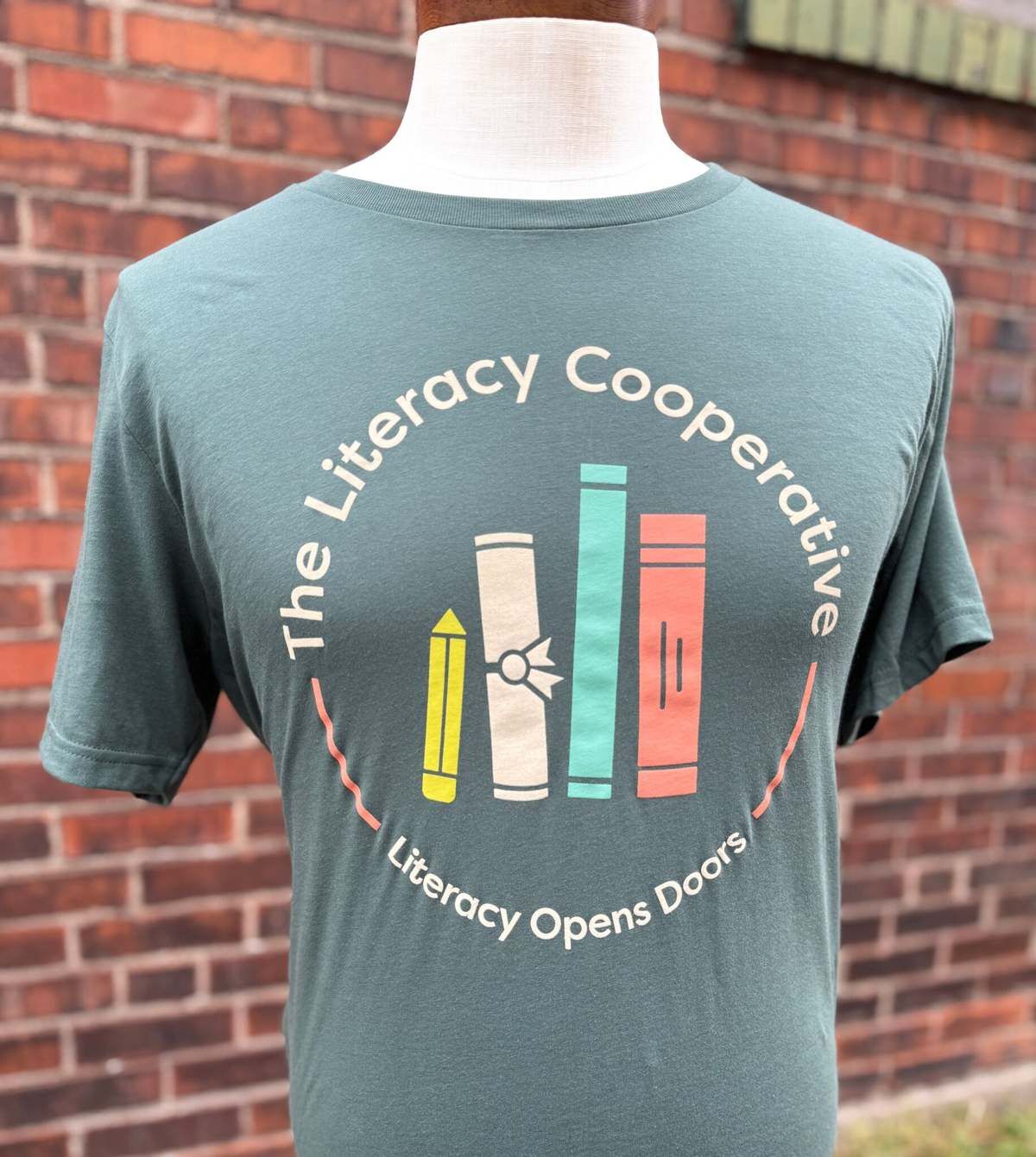 Green T-shirt printed with The Literacy Cooperative logo
